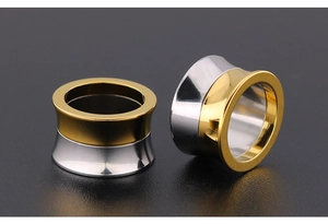 Macro shot of two-tone gold and silver stainless steel ear tunnels with polished finish