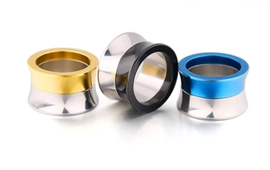 Close-up of polished double flare ear gauges in gold, black, and blue stainless steel