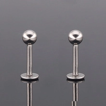 Gros plan sur une paire de piercings en acier poli avec embouts boules et dos plat lisse