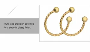 Detailed macro view of gold-plated twisted C-shaped steel piercing rings with ball ends