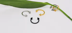 Three-color horseshoe barbells in silver, gold, and black with sharp conical ends