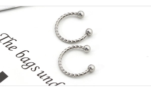 Macro detail of twisted stainless steel horseshoe ring with smooth metal ball ends