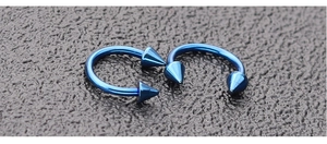 Macro shot of a pair of deep blue stainless steel horseshoe rings with spiked ends