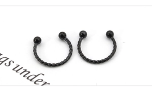 Close-up of black stainless steel twisted horseshoe piercing rings with ball ends