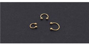 Three gold horseshoe circular barbells in different sizes on textured black background