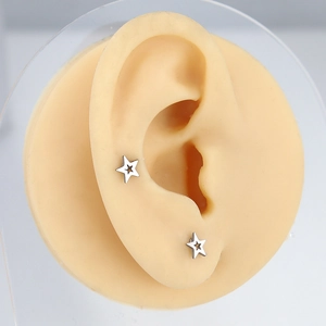 Detail of minimalist star-shaped hollow earrings on a silicone ear model display