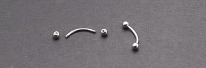 Vue détaillée du piercing barbell courbé en acier poli avec deux billes à visser argentées