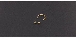 Macro detail of a golden stainless steel horseshoe body piercing ring with small beads