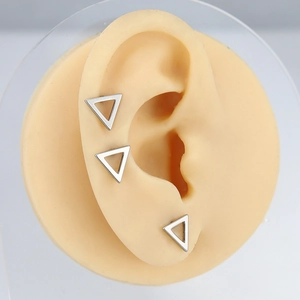 Close-up of minimalist triangle stainless steel stud earring on a silicone ear model