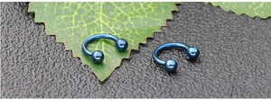 Detail of two dark blue horseshoe circular barbells for nose and ear piercing jewelry