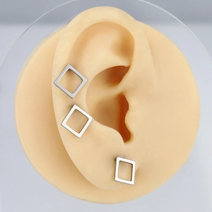 Macro shot of minimalist square hollow earrings with matte brushed metal finish on ear model