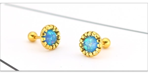 Macro-detail van vergulde titanium stalen oorbellen met ronde blauwe opaalstenen