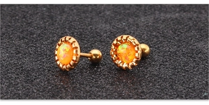 Detail van een goudkleurige titanium stalen oorknop met oranje opaal en getande rand