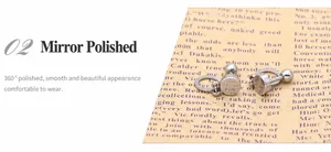 Close-up of 360-degree mirror polished stainless steel stud earrings on paper