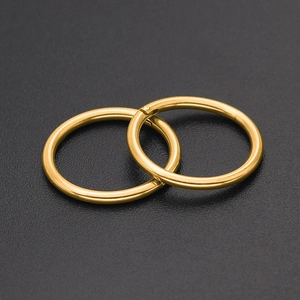 Boucles d'oreilles créoles dorées en acier inoxydable et anneaux de piercing sur fond noir