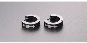 Macro shot of black titanium steel ear hoops with silver star patterns and matte finish