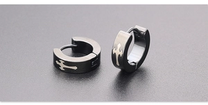 Detail of matte black stainless steel huggie earrings featuring silver cross engraving