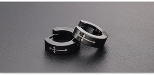 Macro shot of matte black stainless steel hoop earrings with laser engraved arrow patterns