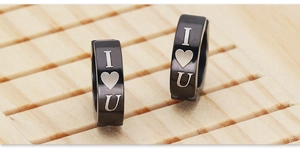 Dettaglio di orecchini a clip in acciaio nero con incisione cuore I Love U e cerniera