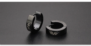 Macro detail of black stainless steel earrings featuring silver flame tribal patterns