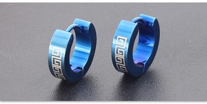 Macro shot of blue stainless steel hoop earrings with golden Greek key pattern detail