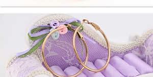 Detail of gold hoop earrings on a purple miniature sofa display with fabric roses