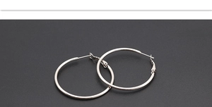 Detailed top view of polished silver hoop earrings on a dark grey textured background