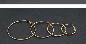 Detailed set of four polished gold hoop earrings in various sizes on a dark background