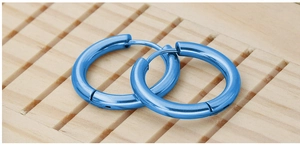 Detail view of glossy blue stainless steel hoop earrings on light wood texture