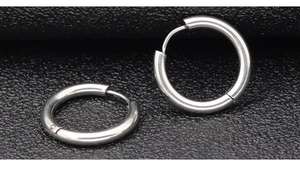 Macro shot of silver-colored polished stainless steel hoop earrings on black texture