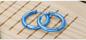 Macro shot of polished bright blue stainless steel hoop earrings on light wood background