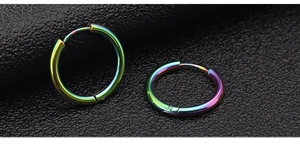 Macro shot of colorful rainbow titanium steel hoop earrings on black leather surface