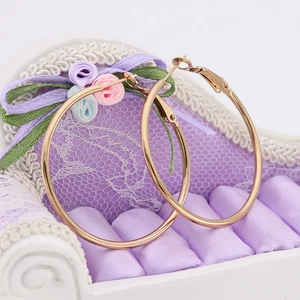 Chic polished gold hoop earrings for women presented on a miniature purple sofa display