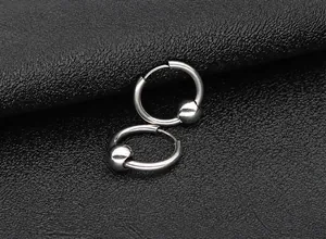 Detailed shot of silver titanium steel hoop earrings with smooth bead on leather background