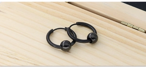 Detail view of black titanium hoop earrings with movable beads on a wooden surface