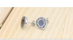 Macro-opname van zilveren titanium stalen oorbellen met zwart emaille en Grieks patroon