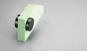 Detail shot of black round magnetic clip earrings showing strong suction on a green stand