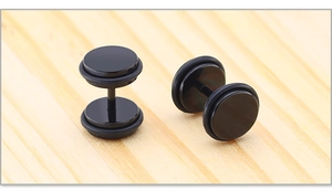 Macro-opname van zwarte barbell oorbellen met rubberen ringen op een houten blad