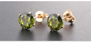 Detail view of 7mm olive green AAA zircon studs with gold plated four-prong setting
