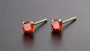 Vista macro di orecchini a lobo con zircone arancione 3mm e montatura a quattro griffe