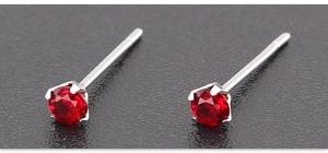 Dettaglio degli orecchini con zircone rosso e montatura a quattro griffe in acciaio