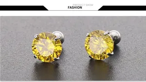 Macro-opname van 7mm gele zirkoon oorknopjes met zilveren vierklauwige zetting op metaal