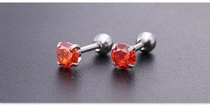 Detalle macro de pendientes de acero de titanio plateado con circonitas naranjas en garras
