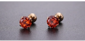 Vista macro de pendientes de circonita roja de 4mm con cierre de bola dorada a rosca