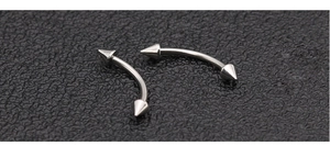 Detail of silver stainless steel curved barbell body piercing with spike ends on black