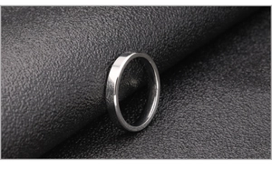 Polierter silberner Edelstahlring mit glatter Metalloberfläche auf dunklem Leder