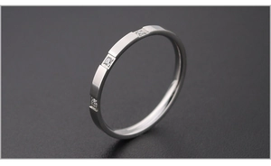 Macro shot of silver stainless steel ring featuring geometric square pattern and zircon inlay