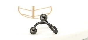 Macro detail of black spiral titanium steel piercing ring on a decorative ceramic tray