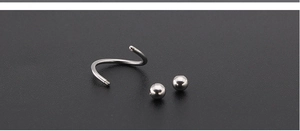 Macro view of spiral titanium steel barbell with screw-off metal beads for piercings