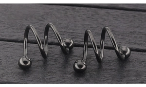Macro shot of two spiral titanium body piercing rings with black polished ball ends